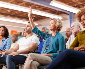 People sat at a public meeting with hands raised