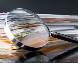 close up of magnifying glass resting on piles of paper