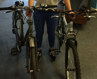 Woman holding two push bikes