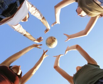 Four young people throwing a ball