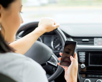 Woman at the wheel of a car viewing her mobile phone