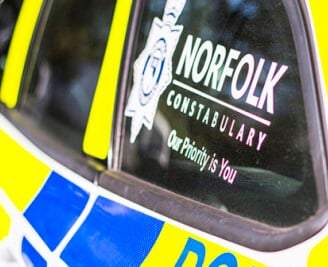 Side of police car with Norfolk Constabulary logo