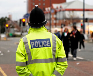 Back view of police officer outside wearing high visibility jacket 