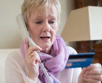 Older female talking on phone reading back card details