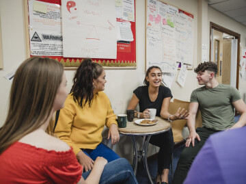 Group of young people sat talking around a table